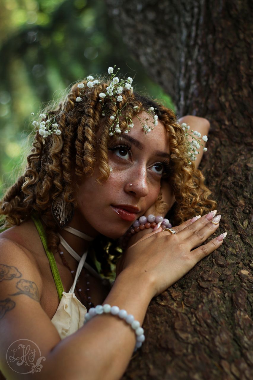 Portrait of young woman resting against a tree branch